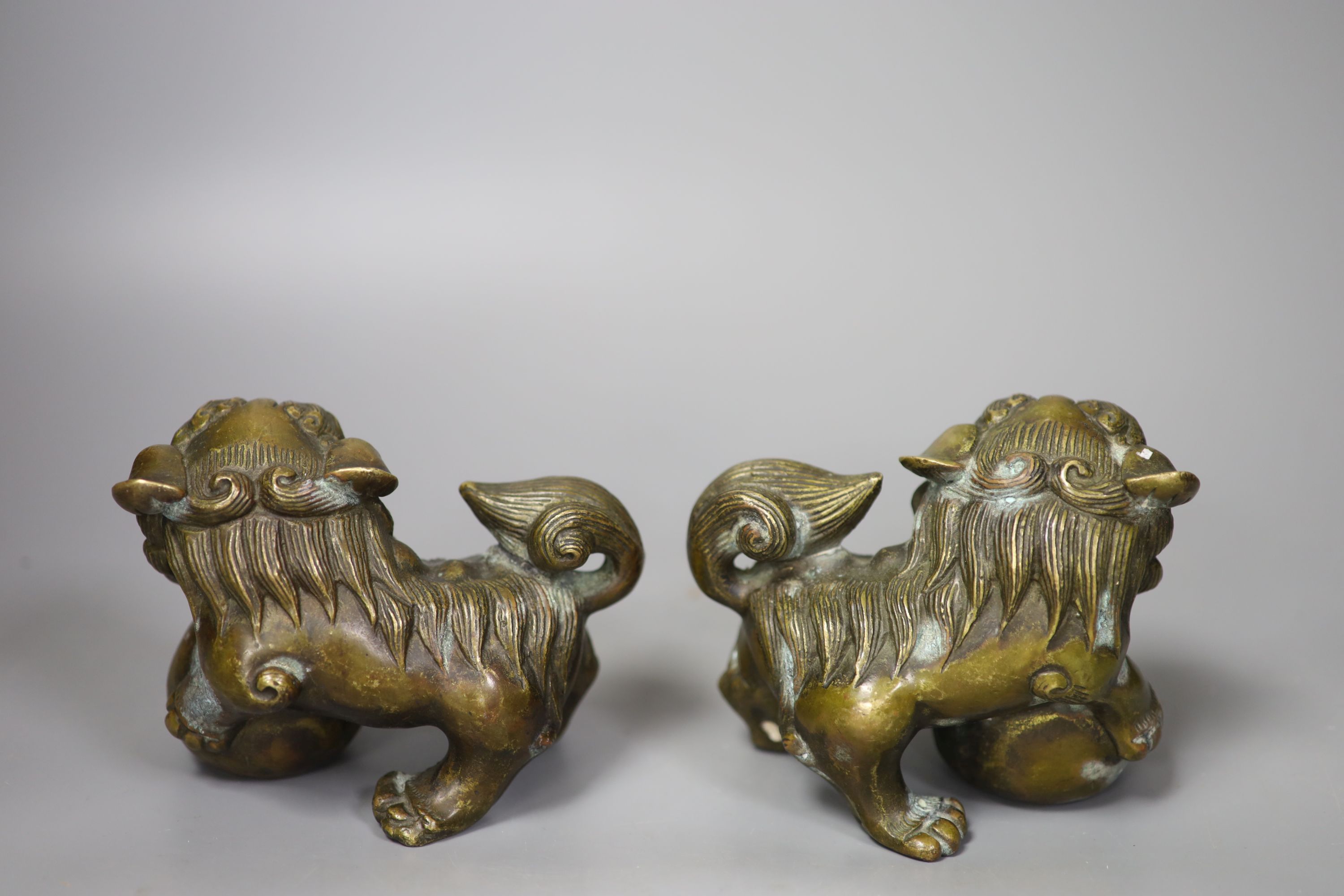 A pair of 20th century cast metal Chinese temple lions (filled). 11cm. long, 11cm. high.